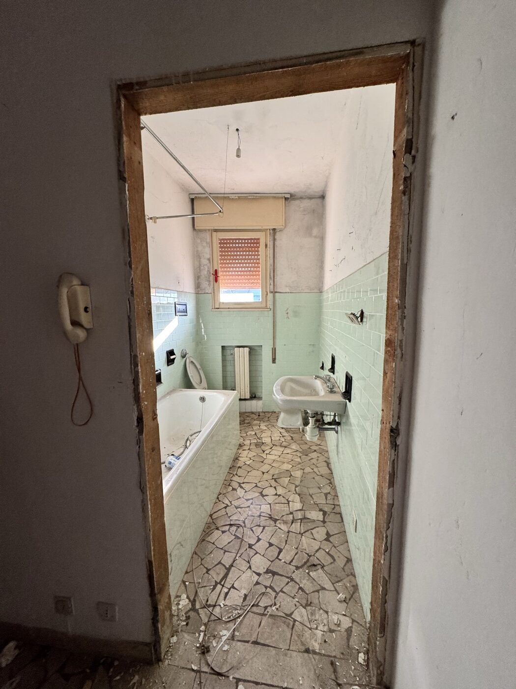 Bagno originario con piastrelle verdi, vasca e sanitari da sostituire
